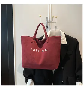 Detailed close-up of a burgundy suede tote bag with white TOTE BAG lettering print