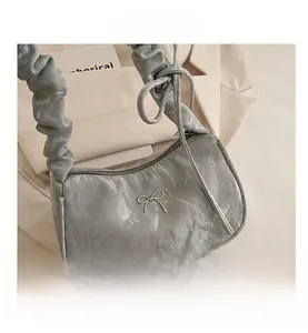 Close-up of silver-grey pleated handbag with metallic bow decoration and mineral texture