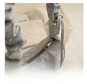 Close-up of cloud-pleated handle and smooth silver metal zipper on grey shoulder bag