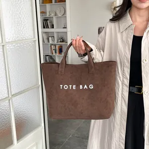 Brown suede tote bag with large white lettering and top handles for daily commuting women