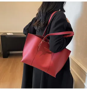 Dettaglio di una grande borsa tote rossa con scritte dorate e spalline sottili