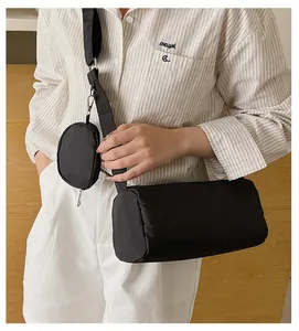Detail of a black nylon cylinder crossbody bag set shown on model in a casual indoor setting