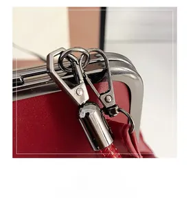 Close-up of premium silver metal hook hardware on a vintage red leather shoulder bag