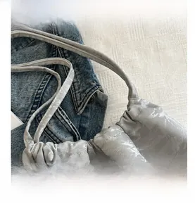 Macro shot of stylish ruched closure and metallic grey texture on crossbody tote bag