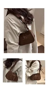 Detail of dark brown leather underarm bag with pleated texture and silver bow buckle
