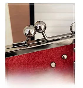 Close-up of red suede bag featuring silver rivets and vintage kiss-lock metal hardware