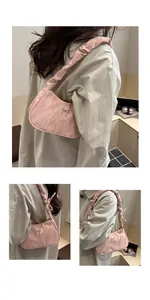 Detail of pink pleated underarm bag featuring a metal bow and ruched shoulder strap