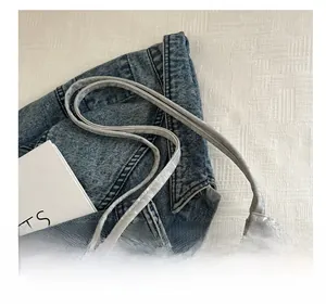 Detail shot of the drawstring closure and slim shoulder strap on a light gray bucket bag