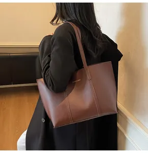 Dettaglio di una grande borsa tote in pelle marrone con scritta dorata Fashion & Bags