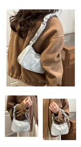 Detailed view of light blue pleated underarm bag featuring a metallic bow and ruched strap