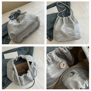 Detail view of light grey pleated shoulder bag with metallic finish and magnetic closure
