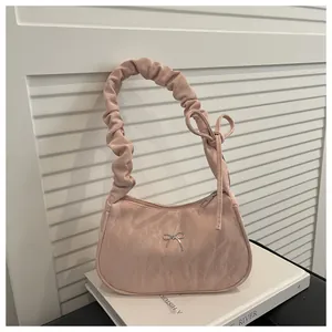 Close-up of pink ruched hobo bag featuring satin texture and decorative ribbon bow detail