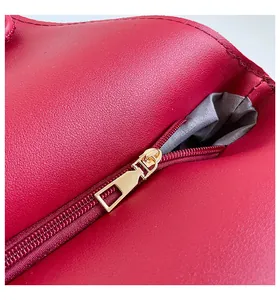 Detail view of the high-quality gold metal zipper on a dark red leather tote bag