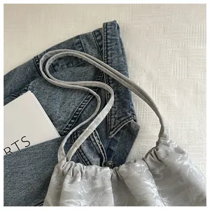Detailed view of silver metallic pleated fabric texture on a drawstring shoulder bag