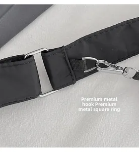 Close-up of silver metal lobster clasp and square ring on a black fabric bag strap