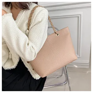 Detailed snake skin embossed tote bag with gold chain strap shown on a model