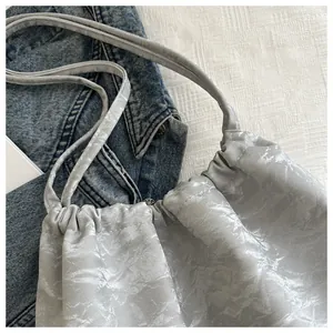 Detailed macro of silver pleated shoulder bag with metallic texture and drawstring closure