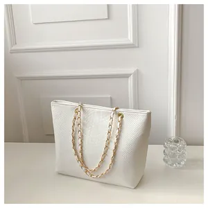 Detail of white crocodile texture leather and gold chain strap on an elegant tote bag
