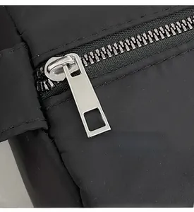 Close-up of smooth silver metal zipper and black fabric texture on the casual bag