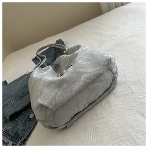 Detailed view of silver butterfly buckle and ruched texture on a chic shoulder bag