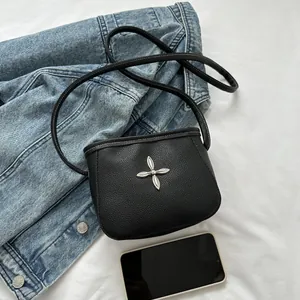 Détail du sac bandoulière en cuir grainé noir avec boucle florale en forme de croix argentée
