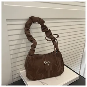 Detail of a brown ruched half-moon bag with a silver bow and cloud-shaped handle