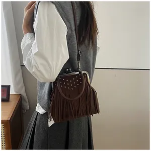 Close-up of vintage brown suede crossbody bag with silver rivets and long tassel detail