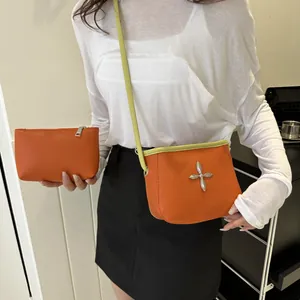 Détail du sac bandoulière en cuir orange avec décorations argentées et bords contrastés