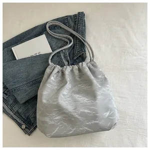 Detail of silver pleated drawstring shoulder bag with cloud texture on white bedding