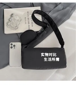 Close-up of black cylinder crossbody bag with wide strap and detachable coin purse