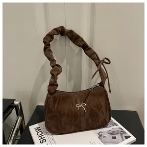 Detail view of coffee brown pleated shoulder bag with silver bow and knot strap