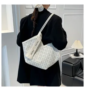 Detailed close-up of a white tweed tote bag with woven texture and branded shoulder strap