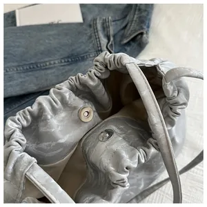 Macro view of silver metallic pleated tote bag with magnetic clasp and drawstring closure