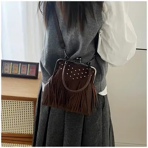 Close-up of vintage dark brown suede bag with silver rivets and long tassel details