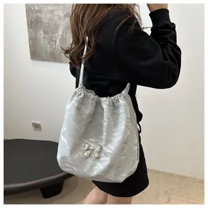 Detail view of silver pleated shoulder bag with chic metal butterfly buckle on grey fabric