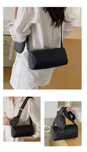 Detail view of a black barrel bag with a small coin purse on a wide shoulder strap