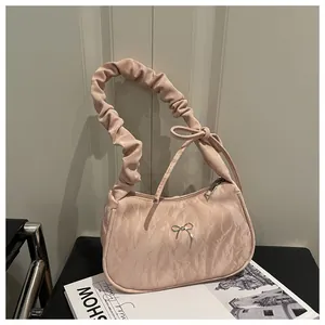 Close-up of pleated pink underarm bag with silver bow detail and ruffled handle strap