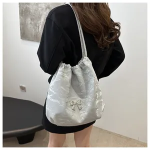 Detail of silver pleated shoulder bag featuring a metallic butterfly ornament and drawstring
