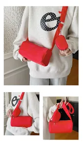 Macro view of red cylindrical nylon crossbody bag with matching mini pouch and metal zipper