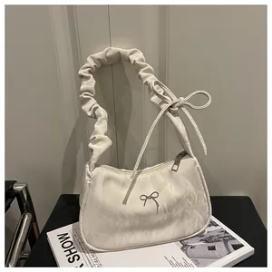 Detail of white pleated shoulder bag with silver bow ornament and chic knot strap