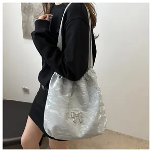 Detailed view of silver shoulder bag with pleated texture and metal butterfly buckle