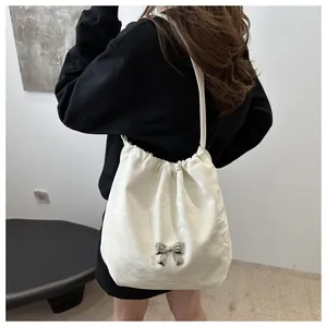 Detail of a creamy white pleated shoulder bag with a silver butterfly ornament on model