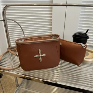 Gros plan sur le sac seau marron texture litchi et sa pochette assortie en métal