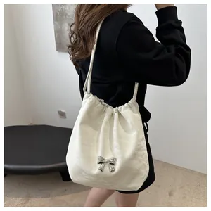 Detail of off-white ruched shoulder bag featuring silver butterfly and drawstring closure
