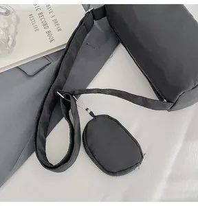 Top view of black nylon crossbody bag with detachable mini pouch on gray suit fabric