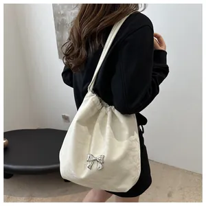 Detail of a creamy white pleated tote bag featuring a silver butterfly metal ornament