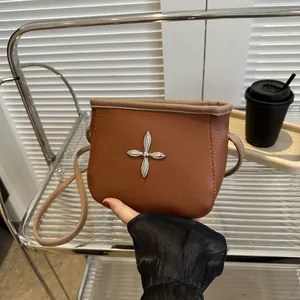 Détail du sac seau en cuir marron avec boucle fleur en croix et bandoulière fine