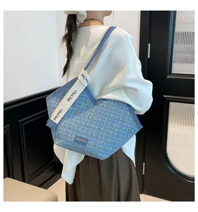 Blue tweed tote bag with V-cut design and printed wide strap shown on model's shoulder