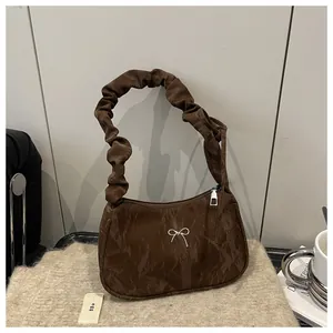 Close-up of brown ruched crescent bag with silver bow detail and ruffled shoulder strap