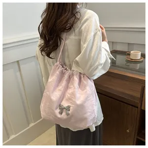 Detail of pink pleated tote bag with metallic butterfly and chain shoulder strap